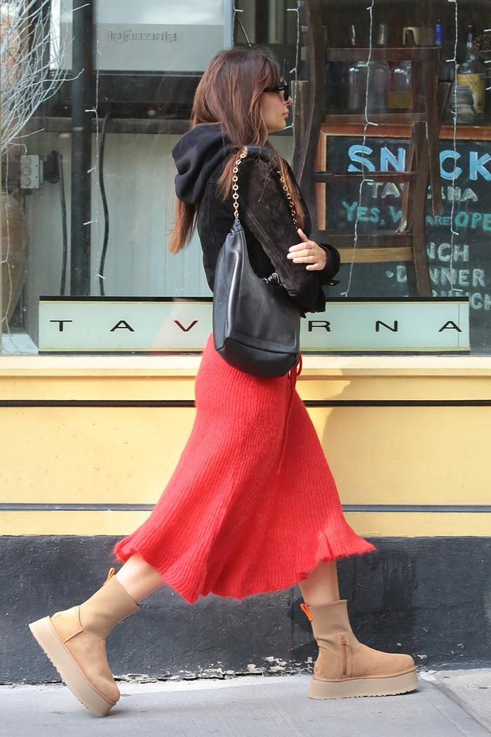 Emily Ratajkowski pairing Ugg Dipper boots with a red knit skirt
